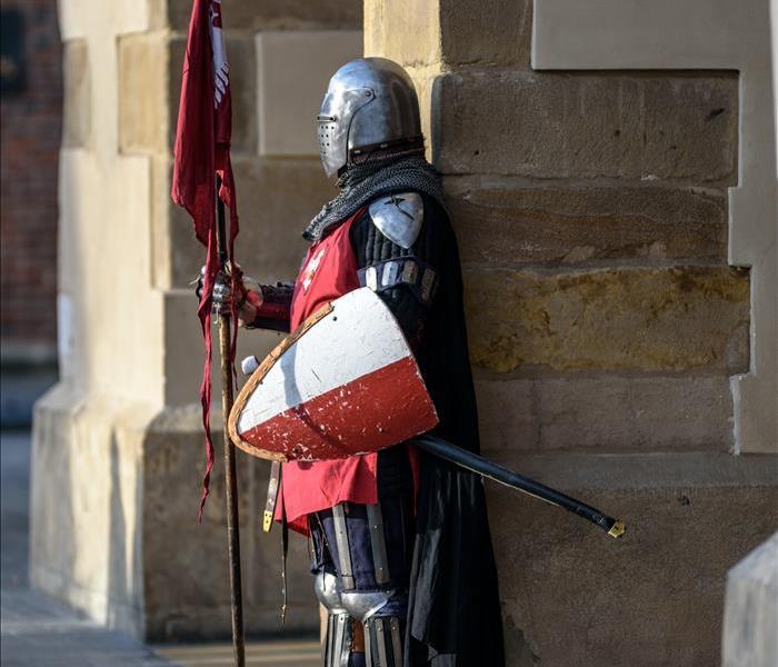 A knight stands outside a castle, at attention